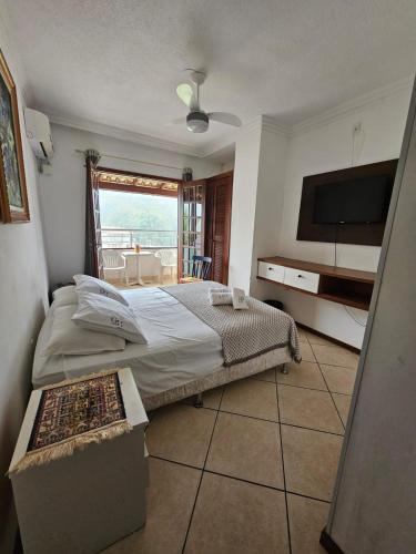 a bedroom with a bed and a flat screen tv at GH Bizkaia in Florianópolis