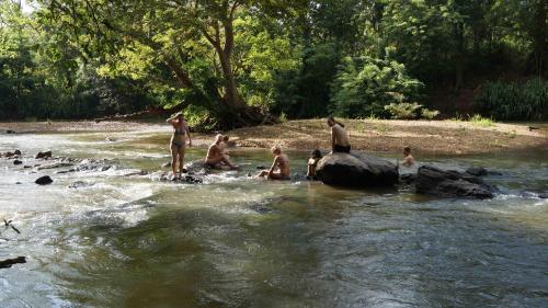 a group of people sitting on rocks in a river at Athgira River Camping - Udawalawe in Udawalawe