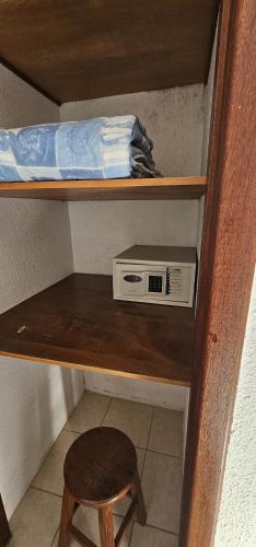 a shelf with a microwave and a stool in a room at GH Bizkaia in Florianópolis