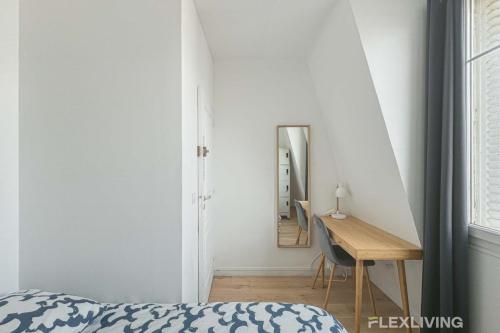 une chambre avec un lit, un bureau et un miroir dans l'établissement Flexliving - room - Houel, à Paris