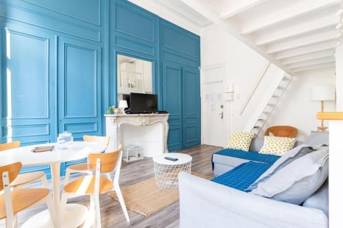 - un salon avec des murs bleus, une table et des chaises dans l'établissement Magnifique appartement - République Beaux-Arts, à Lille