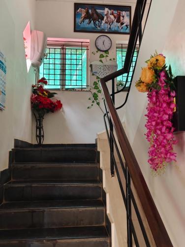 a staircase with flowers and a clock on the wall at SkyView Villa in Candolim