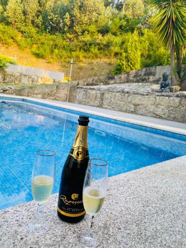 two wine glasses and a bottle of wine next to a swimming pool at Paraiso Relax no Douro in São Cristóvão da Nogueira
