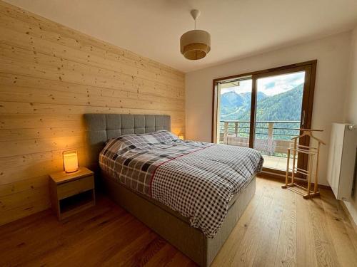 een slaapkamer met een bed en een groot raam bij Thélème A202 - T4 avec vue panoramique sur la station in Châtel