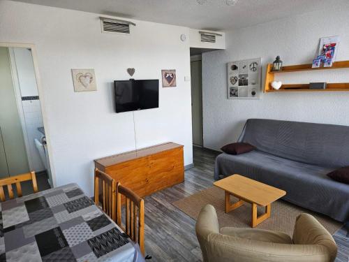 un salon avec un canapé et une télévision dans l'établissement Appartement rénové au pied des pistes avec balcon et parking - FR-1-417-26, à La Toussuire