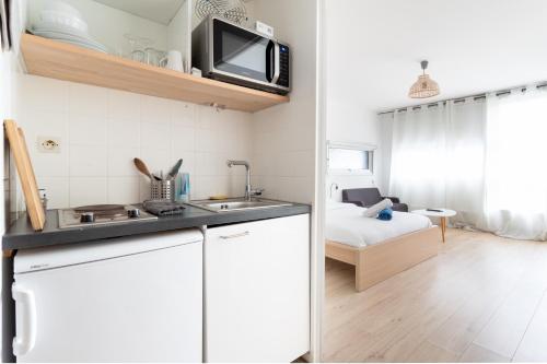 une cuisine avec un évier et une chambre avec un lit dans l'établissement Appartement cosy au cœur de Lille - Euralille, à Lille
