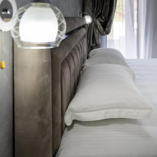 a bed with white pillows next to a window at Casa Patry in Călimăneşti