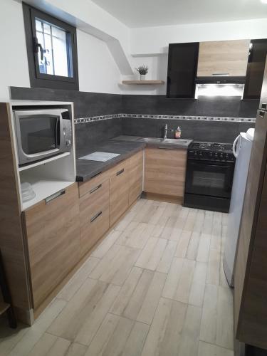 a kitchen with wooden cabinets and a microwave and a television at Gite au Reflet d'Auvers in Auvers-sur-Oise