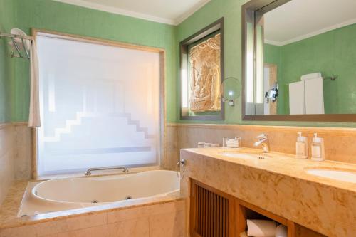 a bathroom with a tub and a sink and a mirror at Iberostar Selection Paraíso Maya - All Inclusive in Puerto Morelos
