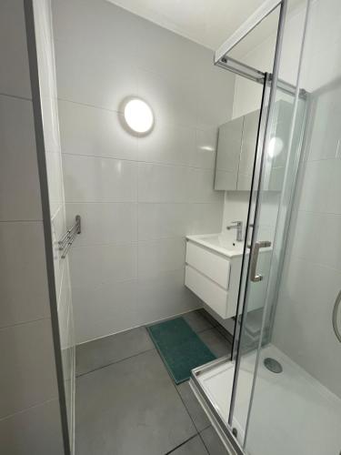 a white bathroom with a shower and a sink at Résidence Agathoise in Agde