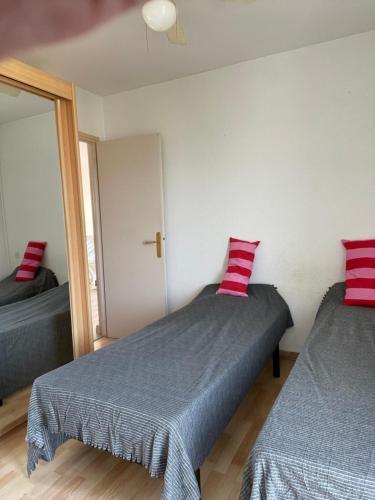 a bedroom with two beds with red pillows on them at Résidence Agathoise in Agde