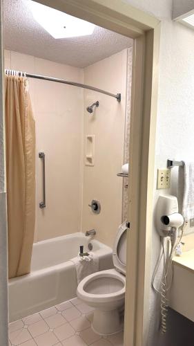 a bathroom with a toilet and a tub and a sink at Executive Inn in Dallas