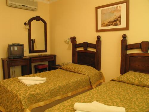 a hotel room with two beds and a mirror at Hotel Bağevleri in Gümbet