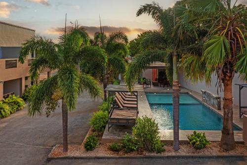 a pool with palm trees and a building at Curadise Living in Willemstad