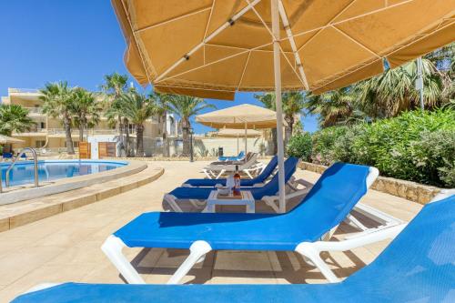 a group of chairs and umbrellas next to a pool at Ta Frenc Apartments in Għasri
