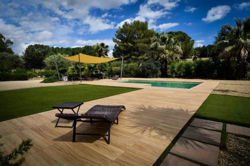 a patio with a table and a bench next to a pool at Folco Studio Apartment in Piazza Armerina