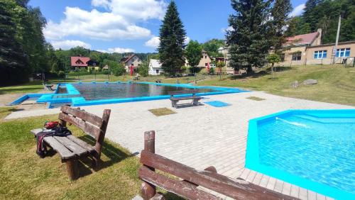 a large swimming pool with a wooden bench next to it at Dvouložnicový apartmán Sluníčko in Zásada
