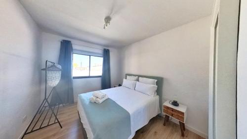 ein Schlafzimmer mit einem weißen Bett und einem Fenster in der Unterkunft DUNASOL Home, by Comfortable Luxury in Corralejo