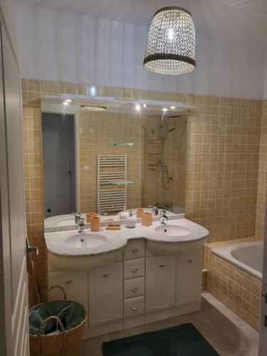 une salle de bain avec deux lavabos, un miroir et une baignoire dans l'établissement Magnifique appartement en centre-ville av parking, à Cavalaire-sur-Mer