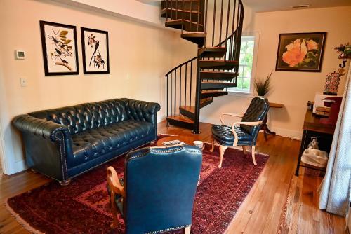 a living room with a leather couch and a staircase at James Armistead Lafayette Cottage in Cumberland Landing