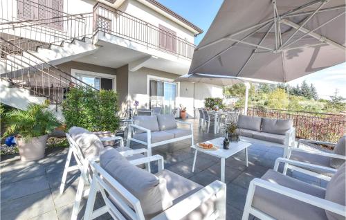 a patio with white chairs and an umbrella at Nice Home In Viagrande With Wifi in Viagrande