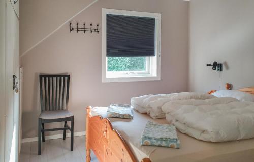 a bedroom with a bed and a chair and a window at 5 Bedroom Lovely Home In Bjoa in Utbjoa
