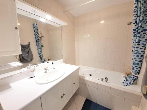 La salle de bains blanche est pourvue d'un lavabo et d'une baignoire. dans l'établissement Appartement dans résidence calme, à Montpellier