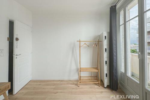 une pièce avec un mur blanc et une échelle en bois dans l'établissement Flexliving - room - Houel, à Paris