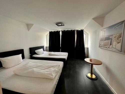 a small room with two beds and a table at Hotel Specht by Trotmannia in Dortmund