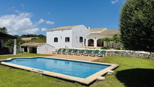 a swimming pool in front of a white house at Holiday Home Finca Binimazoch in Punta Grossa