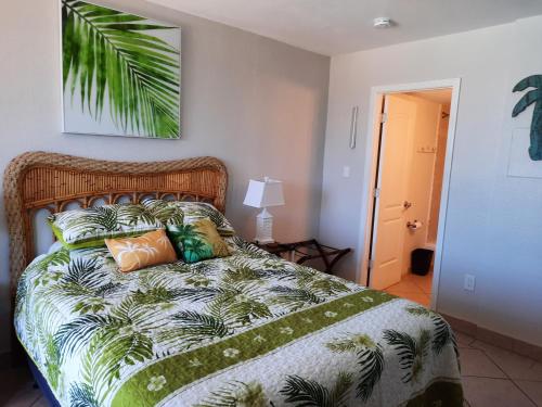 a bedroom with a bed with a green and white comforter at Daytona Beach Hawaiian Inn in Daytona Beach