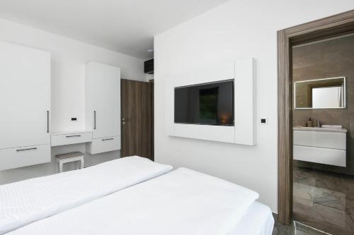 a white bedroom with a bed and a tv at Holiday Villa MI in Orebić