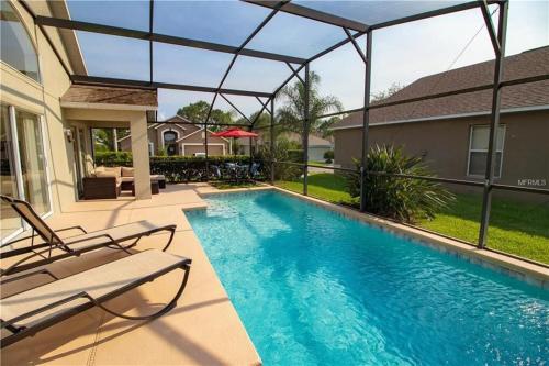 a swimming pool with two chairs next to a house at Updated Pool Villa - Southern Dunes in Haines City