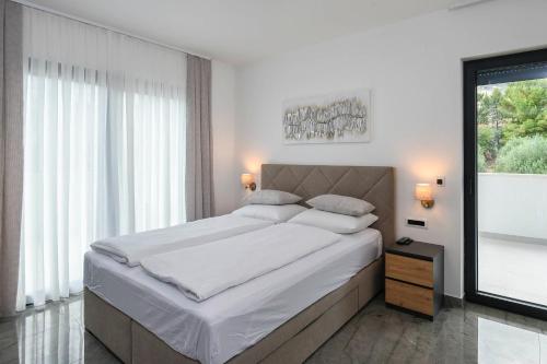a white bedroom with a large bed and a window at Holiday Villa MI in Orebić