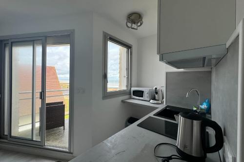 une petite cuisine avec un four micro-ondes et une fenêtre dans l'établissement Nice T2 with 2 balconies on the seafront, à Ouistreham