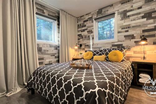 a bedroom with a black and white bed and windows at Le2089 - Spa et plage - Les chalets dans le nord in Sainte-Lucie-de-Doncaster