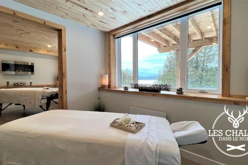 a bedroom with a bed and a large window at Le2089 - Spa et plage - Les chalets dans le nord in Sainte-Lucie-de-Doncaster