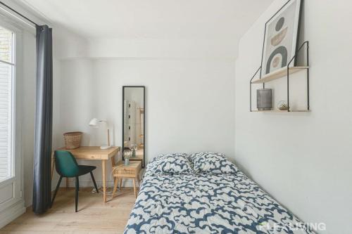 une chambre avec un lit, un bureau et un miroir dans l'établissement Flexliving - room - Houel, à Paris
