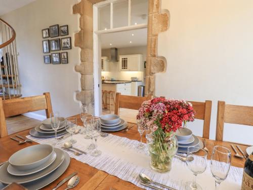 a dining room table with a vase of flowers on it at Clock Tower in Grange Over Sands