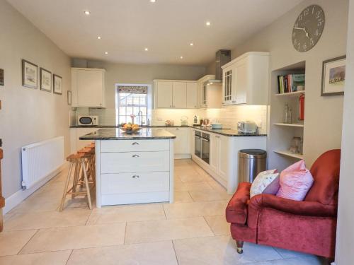 a kitchen with white cabinets and a red chair at Clock Tower in Grange Over Sands