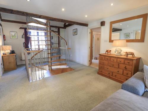 a living room with a spiral staircase and a wooden dresser at Clock Tower in Grange Over Sands