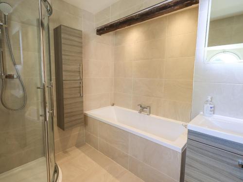 a bathroom with a shower and a tub and a sink at Clock Tower in Grange Over Sands
