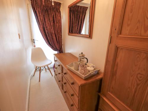 a room with a wooden dresser with a chair and a mirror at Clock Tower in Grange Over Sands