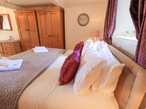 a bedroom with a bed with red and white pillows at Clock Tower in Grange Over Sands