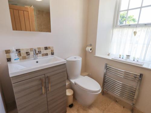 a bathroom with a toilet and a sink and a window at Clock Tower in Grange Over Sands
