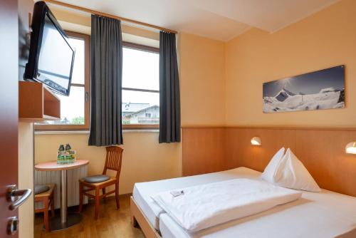 a hotel room with a bed and a table at JUFA Hotel Kaprun - Summercard included in Kaprun