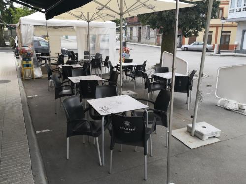 a group of tables and chairs under an umbrella at Pensión Plaza in Quintáns