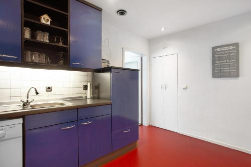 a kitchen with blue cabinets and a red floor at Gästehaus Roth in Willingen