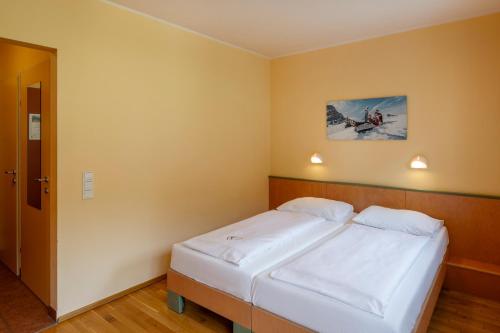 a bedroom with a large bed with white sheets at JUFA Hotel Kaprun - Summercard included in Kaprun