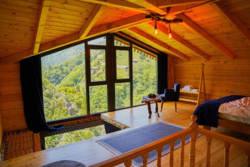 a bedroom with a large window in a log cabin at Depani Doğa Evleri in Kise